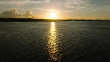 Altın güneş ışığı, gün batımında sakin okyanus ufkunu yansıtır. Siargao, Filipinler.