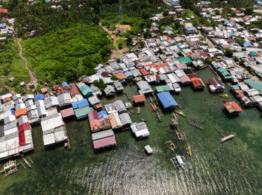 Renkli çatıları ve kıyıya demirlemiş küçük tekneleri olan kümelenmiş yapışık evler. Siargao, Filipinler.