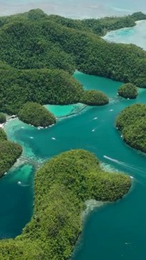 Turkuaz gölleri ve derin mavi denizde küçük tekneleri olan yeşil adalar kümesi. Sugba Mavi Göl, Siargao, Filipinler.