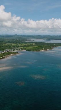 Mercan resifli kıyı şeridi manzarası ve iç kısımlardaki yeşil tepeler. Siargao, Filipinler.