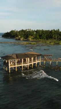 Rıhtım ve tropikal kıyı şeridinde sörfçülerle birlikte bir kulübe. Bulut 9 Sörf Alanı. Siargao, Filipinler.