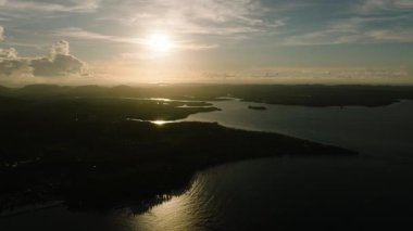 Deniz ve kara siluetleri üzerinde bulutlarla ufukta altın günbatımı. Siargao, Filipinler.