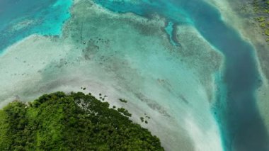 Turkuaz sığ deniz, yeşil bir sahil tepesinin yanındaki kıyı şeridine kadar uzanır. Siargao, Filipinler.