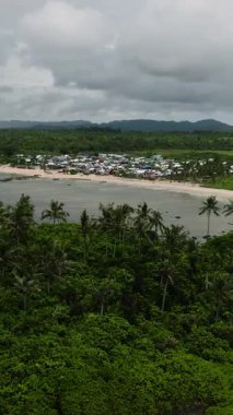 Köy evleri ve kumlu sahildeki orman tepeleri ile tropik sahil şeridi. Siargao, Filipinler.