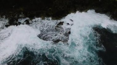 Güçlü beyaz dalgaların hava görüntüsü bulutlu gökyüzünün altındaki sivri kayalıklara çarpar. Siargao, Filipinler.