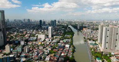 Şehir manzarası: Nehir kenarındaki modern binaların, otellerin ve evlerin insansız hava aracı görüntüsü. Manila, Filipinler.