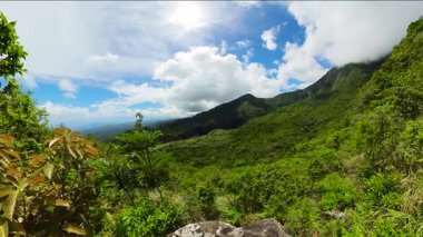 Yeşil bitkileri ve ormanları olan dağ tepeleri. Mavi gökyüzü ve bulutlar. Dauin, Zenci Doğulu. Filipinler.