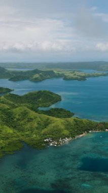 Göl ve turkuaz deniz ufka kadar uzanan kıyı tepelerinin insansız hava aracı görüntüsü. Siargao, Filipinler.