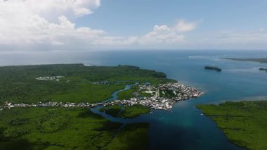 Mangrov ormanının havadan görünüşü, deniz kıyısındaki bir köy ve küçük adaların yanında birleşiyor. Siargao, Filipinler.