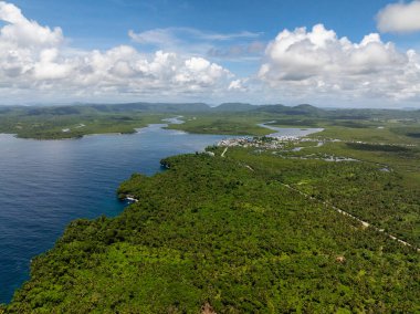 Tropikal kıyı şeridi, mangrov ormanlarını ve uzak dağlarla çevrili kıyı kasabalarını gösteriyor. Siargao, Filipinler.