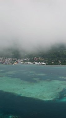 Deniz kıyısında bulutların altında turkuaz sığ su ve mercan resifleri olan bir kasaba. Siargao, Filipinler.