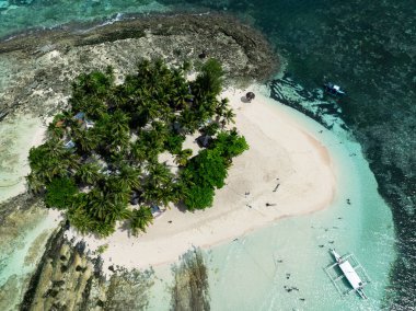 Palmiye ağaçları ve turkuaz su ve mercan resifleriyle çevrili kumlu bir ada manzarası. Guyam Adası. Siargao, Filipinler.