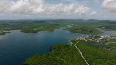 Köy mangrov ormanının yanında uzanır kıvrımlı nehirler bulutların altından denize akar. Siargao, Filipinler.
