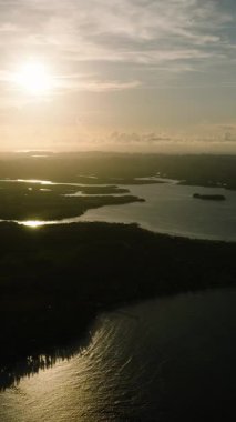 Altın güneş ışığı körfeze ve sahil tepelerine yayılıyor. Siargao, Filipinler.