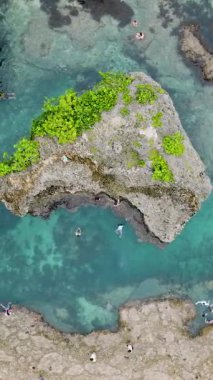 Büyük kayaların arasında yüzen ve berrak suda dinlenen insanların oluşturduğu bir turkuaz havuz. Siargao, Filipinler. Magpupungko Gelgit Havuzu.