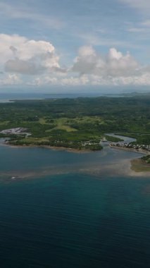 Kıyıya yakın evleri olan yeşil tepeler ve okyanuslarla çevrili bir sahil köyü. Siargao, Filipinler.