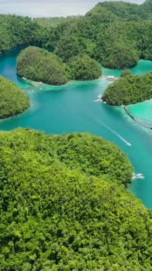 Birkaç tekne turkuaz mavi lagün ve yemyeşil adacıklar arasında yol alıyor. Sugba Mavi Göl, Siargao, Filipinler.