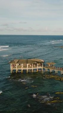 İskelenin sonundaki kulübeyi okyanus dalgaları ve sörfçülerle görmek. Bulut 9 Sörf Alanı. Siargao, Filipinler.