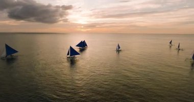 Bulutlu günbatımı geçmişiyle denizde gezinen yelkenliler. Boracay, Filipinler.
