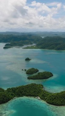 Kıyı manzarası ve bulutlu gökyüzü ile mavi denize saçılmış küçük yeşil adacıklar. Sugba Mavi Göl, Siargao, Filipinler.