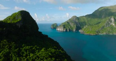 Beyaz kumlu ve tekneli adaların insansız hava aracı görüntüsü. Mavi gökyüzü ve bulutların altında mavi deniz. El Nido, Palawan. Filipinler.