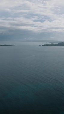 Bulutlu gökyüzünün altındaki birkaç kıyı adasının geniş bir görüntüsü. Siargao, Filipinler.