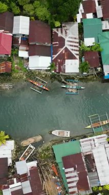 Köyler ve geleneksel tekneler tropik soğuk bahar nehrinde ilerliyorlar. Surigao del Sur 'da Bogac Soğuk Baharı. Filipinler. Dikey görünüm.