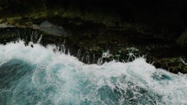 Köpüklü turkuaz okyanus dalgaları kayalık kıyı şeridine çarpıyor. Siargao, Filipinler. Yavaş Hareket.