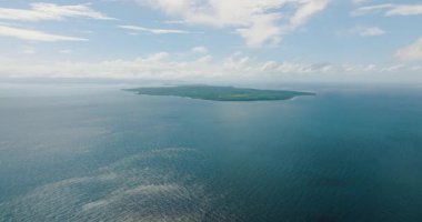 Mavi deniz, güneş yansıması ve mavi gökyüzü ve bulutların altında Carabao Adası. Romblon, Filipinler.