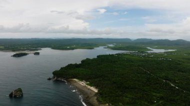 Tropikal ormanlı hava sahili, denize akan nehirler, kıyıdan uzak adalar ve kıyıya yakın uzak bir köy. Siargao, Filipinler.