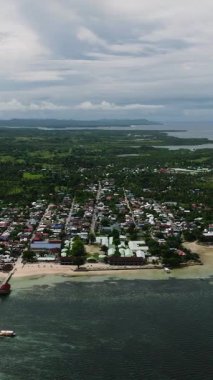 Rıhtım, kıyı şeridi ve çevreleyen yemyeşil manzaralı kıyı kasabasının manzarası. General Luna, Siargao, Filipinler.