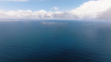 Sakin yüzeyi ve bulutlu parlak gökyüzünün altında ufuk çizgisi olan mavi okyanus. Siargao, Filipinler.