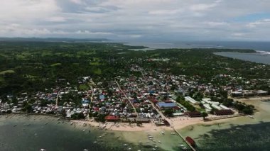 Sahilde, etrafını çevreleyen ağaçlar ve sakin denizlerle dolu renkli evler yığını. General Luna, Siargao, Filipinler.