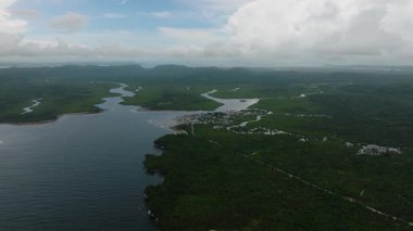 Tropikal orman ve küçük kıyı köyünün yanında denize katılan başıboş nehirler, yeşil manzara ve su yollarının bir karışımı. Siargao, Filipinler.