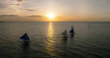 Denizde yüzen teknelerin günbatımı. Boracay, Filipinler.