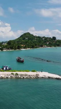 Turkuaz sularda demirli balıkçı tekneleri ve arka planda bereketli bir sahil şeridi olan tropikal bir ada. Ko Samui, Tayland.