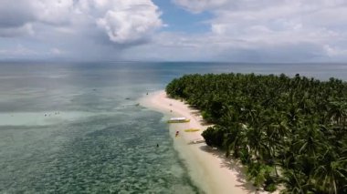 Palmiye ağaçları ve turkuaz sularda yüzen birkaç geleneksel teknesi olan kavisli bir sahil. Siargao, Filipinler. Casa Desideria.