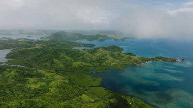 Yuvarlanan orman tepeleri, dağılmış küçük adalarla sakin koylara sınırdır. Siargao, Filipinler.