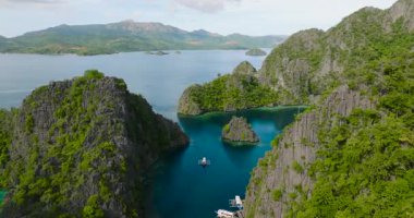 Kireç taşı oluşumları olan bir ada, Kayangan Gölü 'nün etrafında dolaşan tekneler. Coron, Palawan. Filipinler.