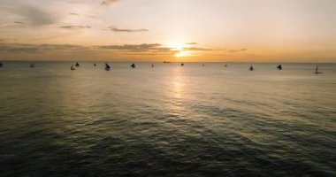 Gün batımının yansımasıyla denizin üzerinde uçmak. Boracay, Filipinler 'de yelkenli teknesi.