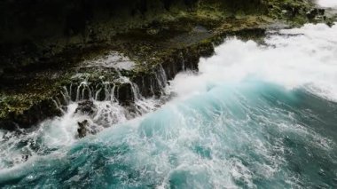 Kıyıdaki sivri kayalıklara çarpan mavi okyanus dalgalarının havadan görünüşü. Siargao, Filipinler. Yavaş Hareket.