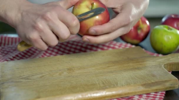 Очищаю яблоко. Руки режут кожуру яблока. Здоровое питание. Вегетарианская еда — стоковое видео