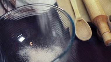 Derin bir cam kaseye düşen krema için pudra şekeri