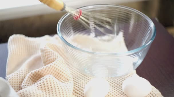 Schneebesen in Glasschüssel vorhanden. Nahaufnahme. Eier auf dem Küchentisch. Hand wirft Schneebesen in eine Schüssel — Stockvideo