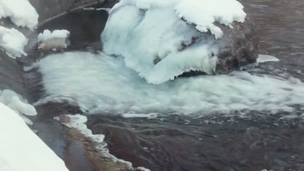 Eisbedeckter Stein. Wasser fließt im Winter in Steinnähe. Nahaufnahme. Winterbach — Stockvideo