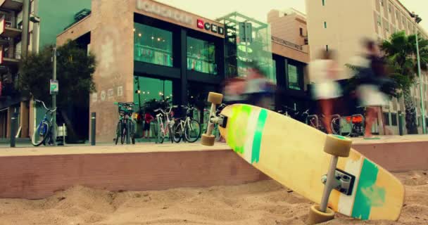 Skateboard lying on sand at city street. Closeup. Time lapse. Urban scene — Stock Video