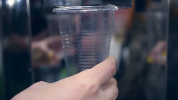 Vatten som rinner in i plastmugg. Närbild av handen håller kopp med vatten — Stockvideo