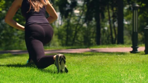 Kvinnan sträcker sig utomhus. Fitness tjej gör utfall i park. Träning och fitness — Stockvideo