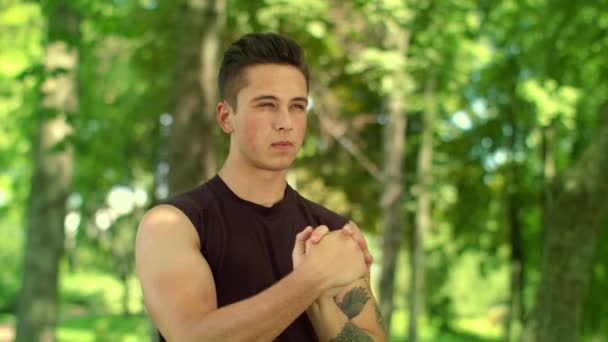 Un uomo che allunga il polso nel parco. Fitness uomo warm up mani all'aperto — Video Stock