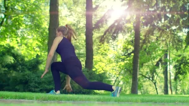 Молодая женщина делает упражнения на открытом воздухе. Подтянутая девушка, делающая зарядку в парке — стоковое видео
